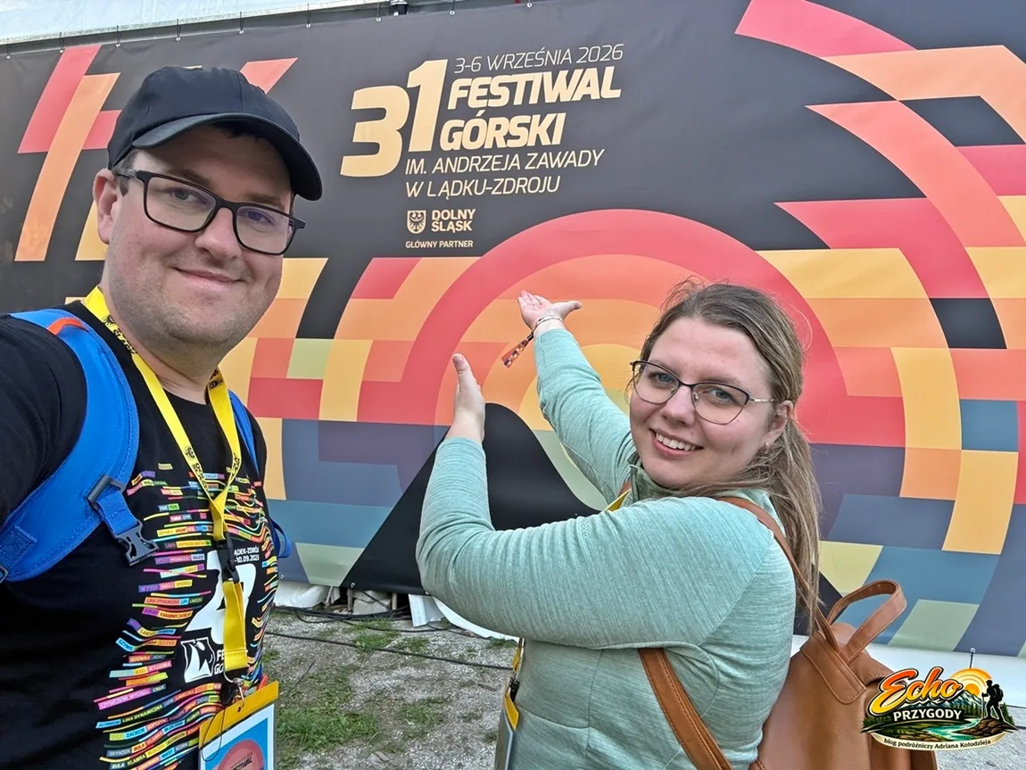 Adrian i Dorotka z bloga Echo Przygody pozują na tle ścianki 31. Festiwalu Górskiego w Lądku-Zdroju.